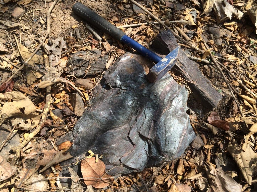 Iron ore specimen with geological hammer near Thailand–Laos border